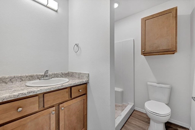 full bathroom featuring a shower stall, baseboards, toilet, wood finished floors, and vanity