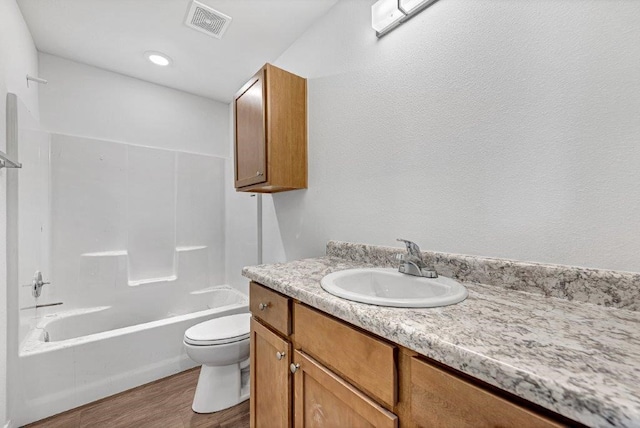 bathroom featuring visible vents, toilet, shower / washtub combination, wood finished floors, and vanity