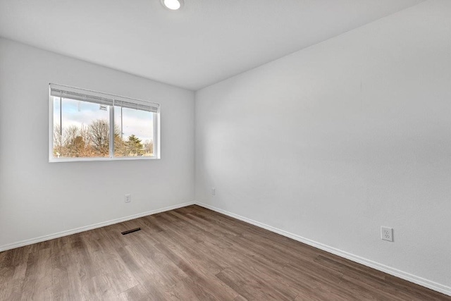 empty room with visible vents, wood finished floors, and baseboards