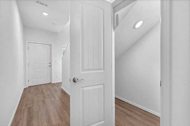 corridor featuring visible vents, baseboards, and wood finished floors