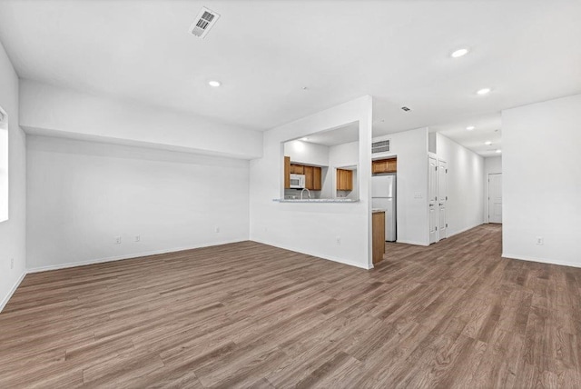 unfurnished living room featuring visible vents, recessed lighting, baseboards, and wood finished floors