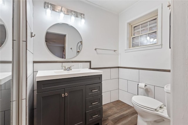 bathroom with hardwood / wood-style floors, vanity, crown molding, toilet, and tile walls