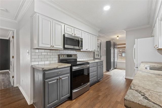 kitchen featuring gray cabinetry, backsplash, appliances with stainless steel finishes, dark hardwood / wood-style flooring, and white cabinetry