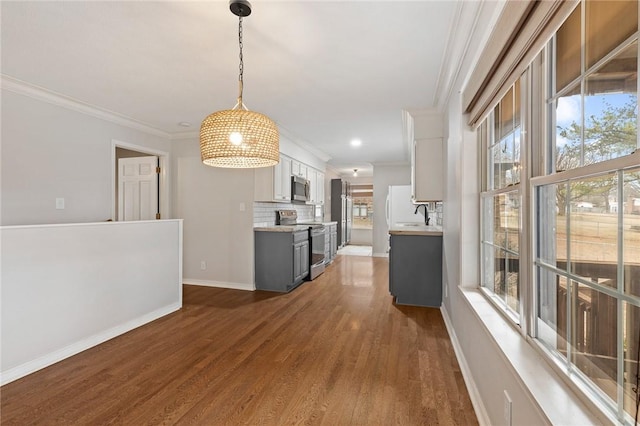 kitchen with backsplash, dark hardwood / wood-style floors, appliances with stainless steel finishes, decorative light fixtures, and white cabinetry