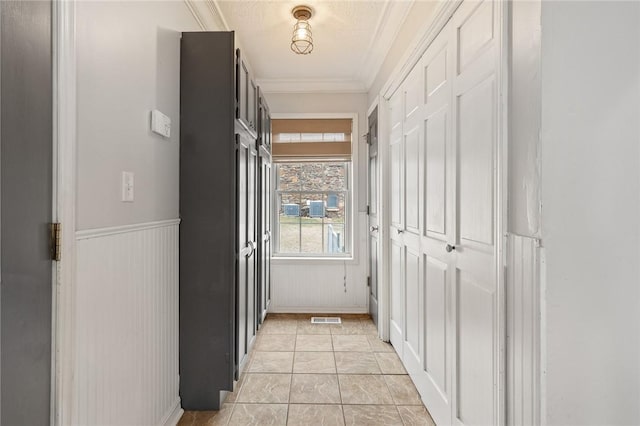 hall featuring light tile patterned floors and crown molding