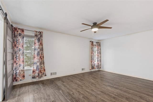 spare room featuring hardwood / wood-style flooring, ceiling fan, and a barn door