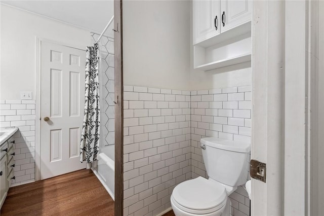 full bathroom featuring vanity, hardwood / wood-style flooring, toilet, shower / bath combo with shower curtain, and tile walls