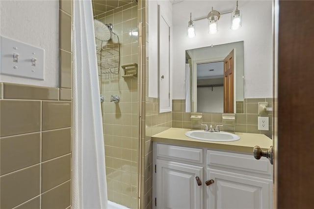 bathroom with a tile shower, vanity, and tile walls