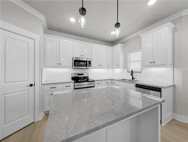 kitchen with pendant lighting, sink, light stone counters, white cabinetry, and stainless steel appliances