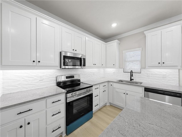 kitchen featuring light stone counters, stainless steel appliances, white cabinetry, and sink