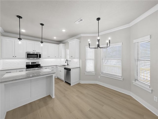 kitchen featuring tasteful backsplash, light stone counters, stainless steel appliances, decorative light fixtures, and white cabinets