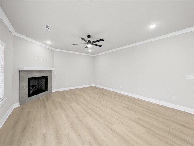 unfurnished living room featuring ceiling fan, crown molding, a tile fireplace, and light hardwood / wood-style flooring