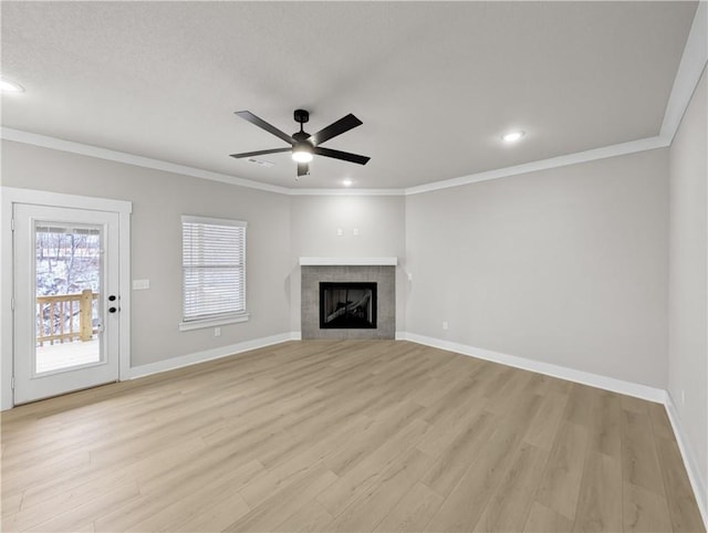 unfurnished living room featuring ceiling fan, light hardwood / wood-style floors, crown molding, and a tile fireplace