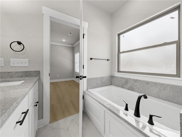 bathroom with a washtub, vanity, a wealth of natural light, and ornamental molding