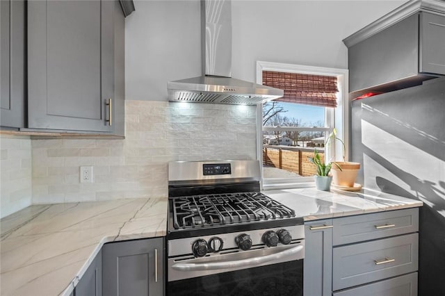 kitchen with gray cabinetry, wall chimney exhaust hood, and stainless steel gas range