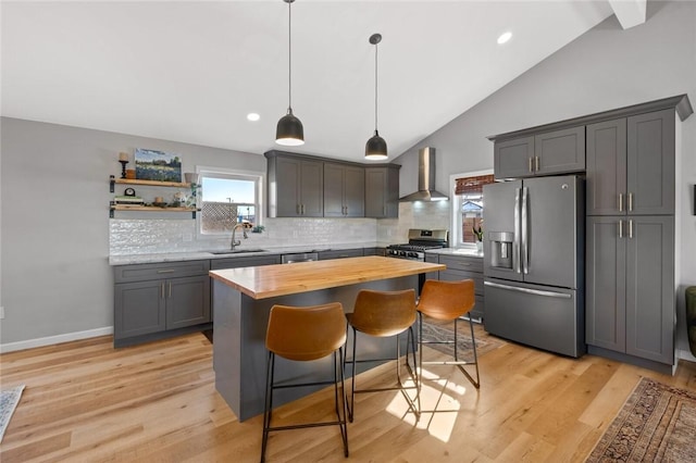 kitchen featuring hanging light fixtures, wall chimney exhaust hood, tasteful backsplash, a kitchen island, and stainless steel appliances