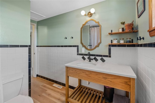 bathroom featuring hardwood / wood-style floors, toilet, sink, and tile walls