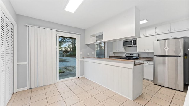 kitchen featuring light tile patterned floors, white cabinetry, appliances with stainless steel finishes, and kitchen peninsula