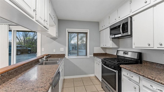 kitchen with light tile patterned floors, stainless steel appliances, white cabinetry, and sink