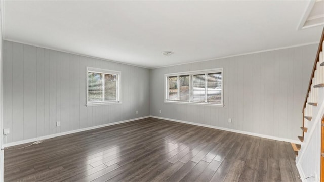 spare room featuring dark wood-type flooring, crown molding, and wooden walls