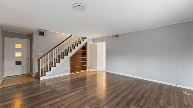 unfurnished living room featuring dark hardwood / wood-style flooring, wooden walls, and ornamental molding