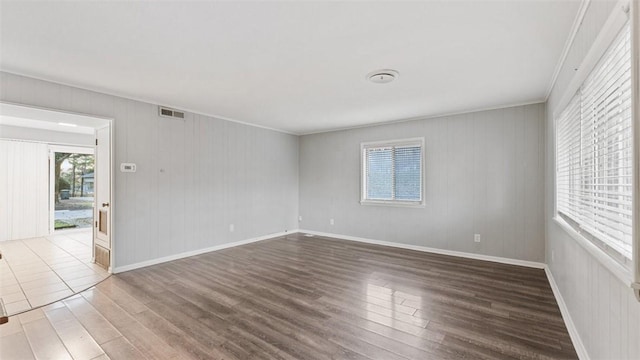 empty room featuring dark wood-type flooring and ornamental molding