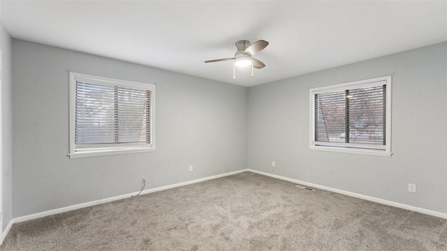 carpeted empty room with ceiling fan and plenty of natural light