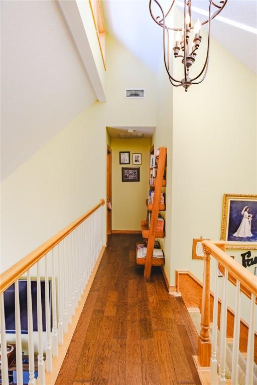 corridor with dark hardwood / wood-style flooring, high vaulted ceiling, and a chandelier