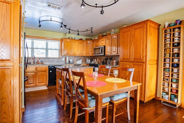 dining room with sink, a textured ceiling, and dark wood-type flooring