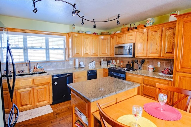 kitchen with light stone countertops, dishwasher, light hardwood / wood-style flooring, and tasteful backsplash