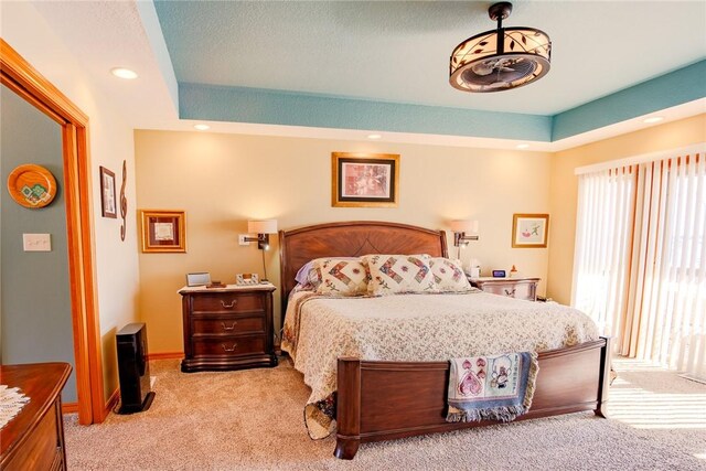 bedroom featuring light colored carpet and a tray ceiling