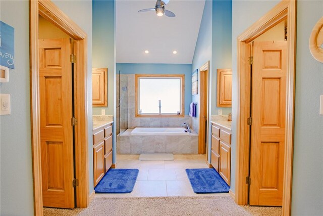 bathroom featuring vaulted ceiling, ceiling fan, tile patterned floors, tiled tub, and vanity