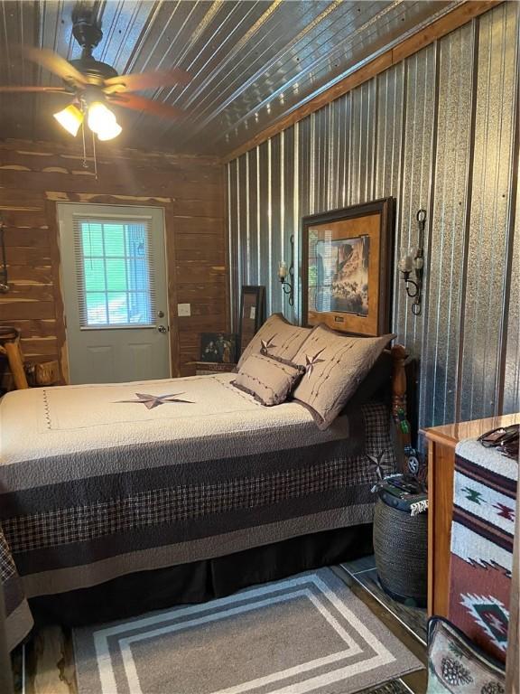 bedroom with wood walls and ceiling fan