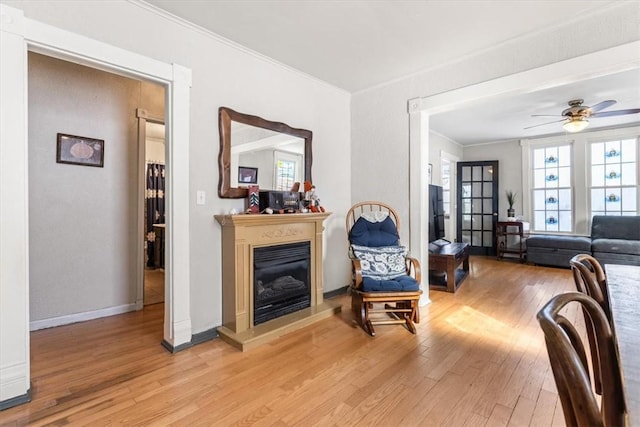 living room with ceiling fan, light wood-type flooring, and ornamental molding