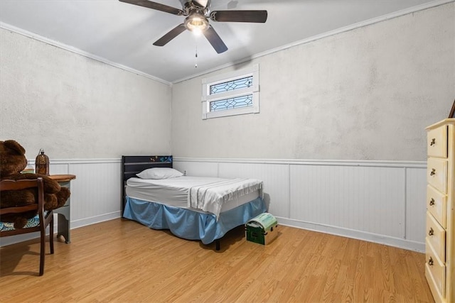 bedroom with light wood-type flooring, ceiling fan, and crown molding