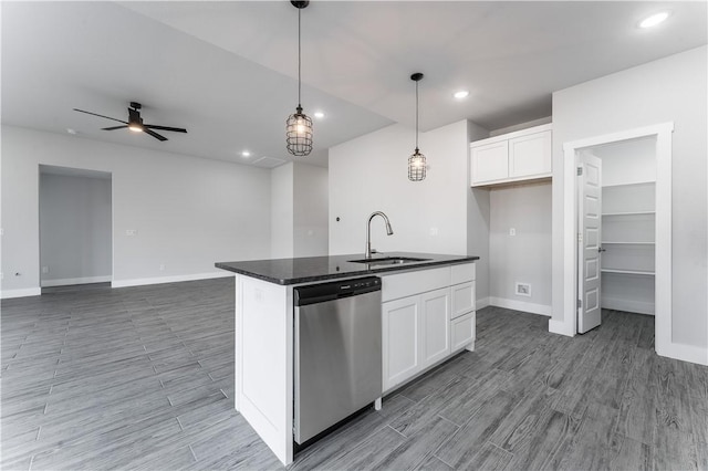 kitchen with a kitchen island with sink, ceiling fan, white cabinets, stainless steel dishwasher, and sink