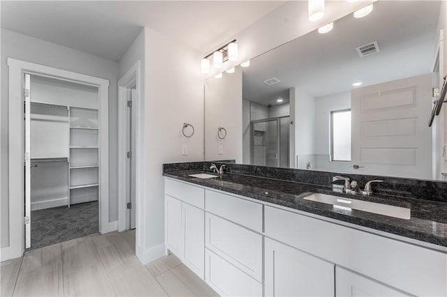 bathroom with a shower with door and vanity