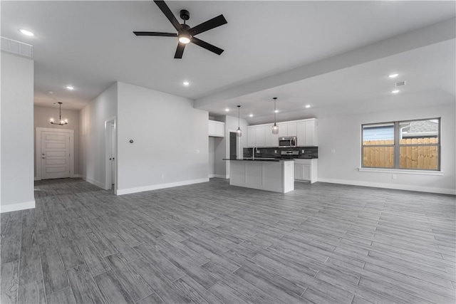 unfurnished living room with ceiling fan with notable chandelier and sink