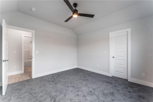 empty room featuring lofted ceiling, ceiling fan, and dark carpet