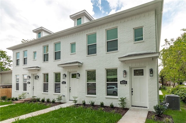 view of front of home with central AC and a front yard