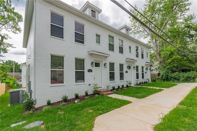 view of front of home with central AC unit and a front lawn