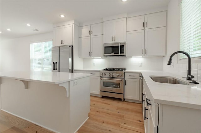 kitchen featuring sink, white cabinetry, light hardwood / wood-style floors, a kitchen island, and appliances with stainless steel finishes