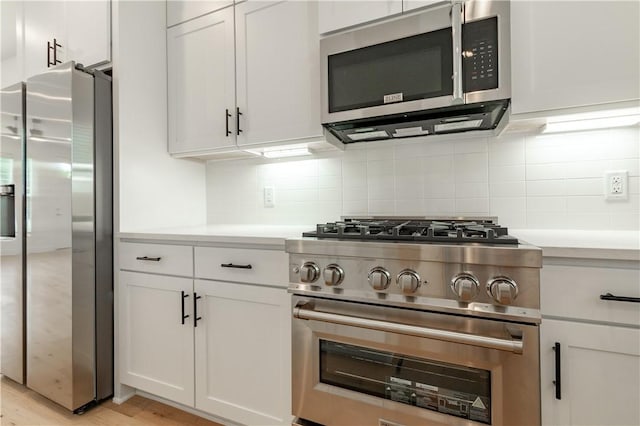 kitchen featuring white cabinets, appliances with stainless steel finishes, backsplash, and light hardwood / wood-style flooring