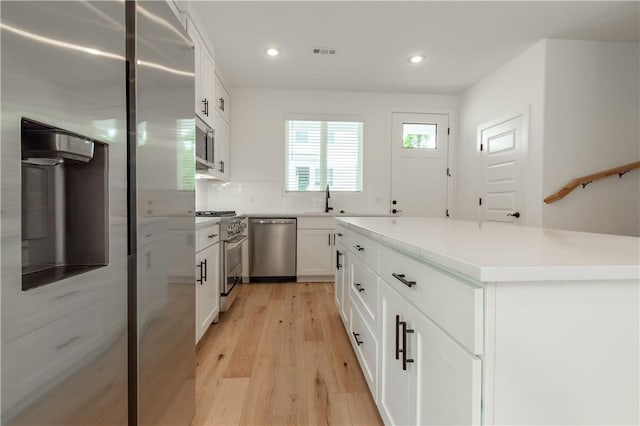 kitchen featuring appliances with stainless steel finishes, a kitchen island, decorative backsplash, white cabinets, and sink