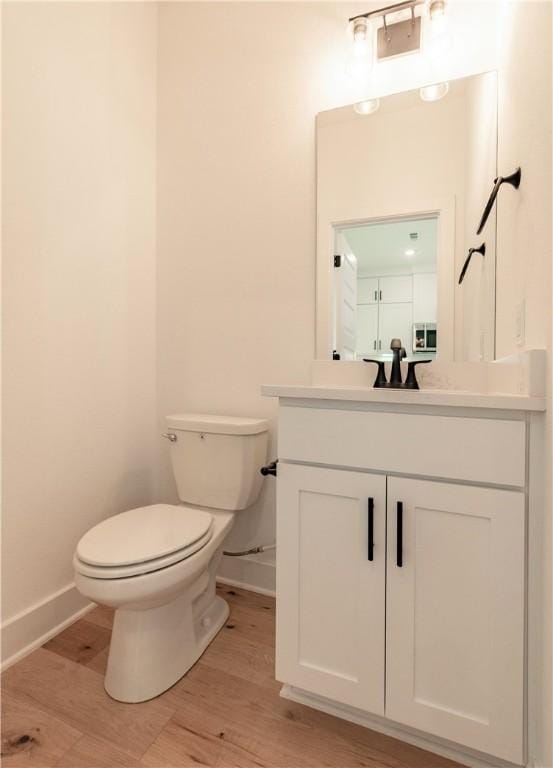 bathroom with toilet, vanity, and hardwood / wood-style flooring