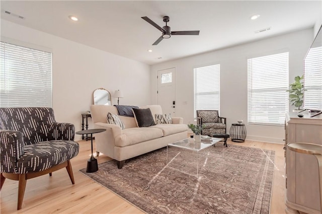 living room with light hardwood / wood-style floors, ceiling fan, and a healthy amount of sunlight