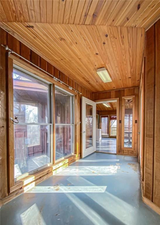 corridor featuring french doors, wooden walls, and wood ceiling