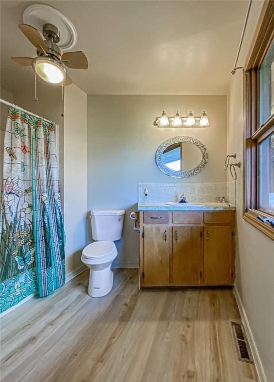 bathroom featuring hardwood / wood-style floors, toilet, a shower with shower curtain, vanity, and ceiling fan