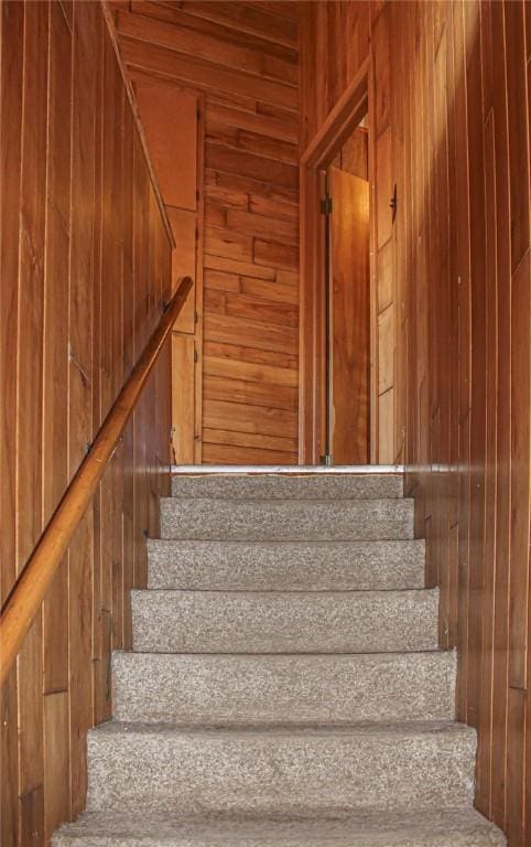 stairway featuring wooden walls