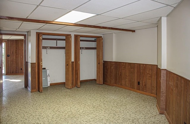 unfurnished bedroom featuring two closets and a drop ceiling